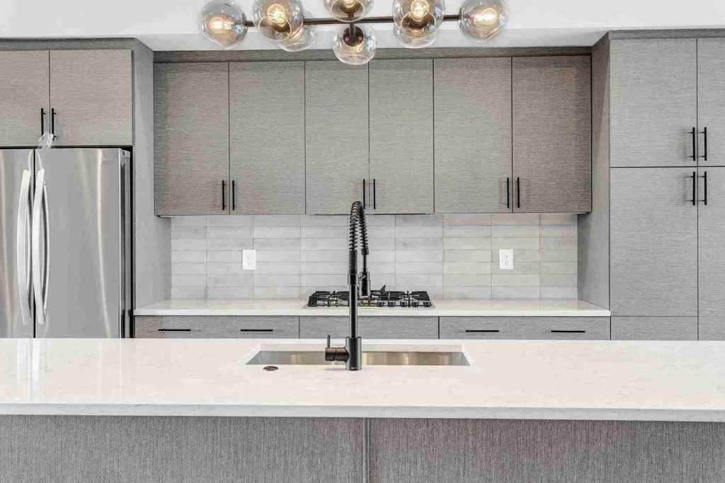 Atlanta contemporary home kitchen with white textured melamine cabinets, island, and modern light.